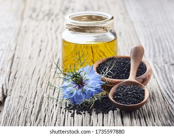 Black Cumin Oil With Flower Nigella Sativa On Wooden Table