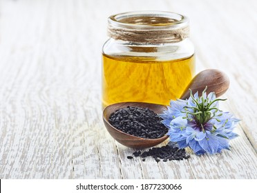 Black Cumin Oil With Flower Nigella Sativa On White Wooden Board