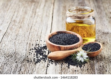 Black cumin oil with seeds and flower nigella sativa on wooden background - Shutterstock ID 1464118283