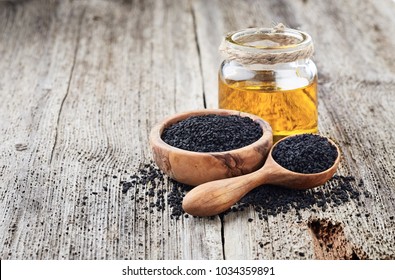 Black cumin oil with seeds on wooden background - Shutterstock ID 1034359891
