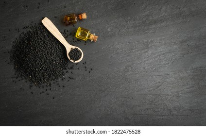 Black Cumin Oil In Small Vintage Bottle On Black Stone Background. Caraway Seeds Organic Essential Oil, Tincture, Extract, Infusion With Copy Space