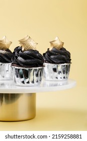 Black Cupcakes Decorated With A Gold Star On A Cake Stand