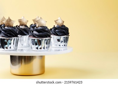 Black Cupcakes Decorated With A Gold Star On A Cake Stand