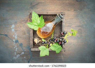 Black Currant Oil And Green Leaves On A Wooden Table Background. Herbal Medicine Concept.