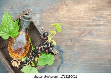 Black Currant Oil And Green Leaves On A Wooden Table Background. Herbal Medicine Concept.