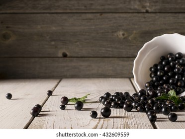 Black currant on wooden table with leaf sprig