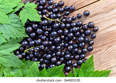 Black Current, Ripe Berries And Green Leaves On  Wooden Table