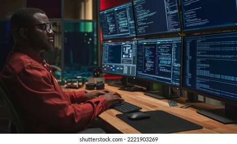 Black Cyber Security Specialist Coding on Desktop Computer With Six Monitors in Dark Office. African American Male Contractor Monitoring Data Protection System For Ministry Of Defence, Private Sector