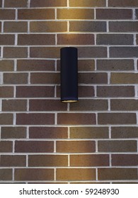 Black Cylindrical Light Fixture On Exterior Brick Wall