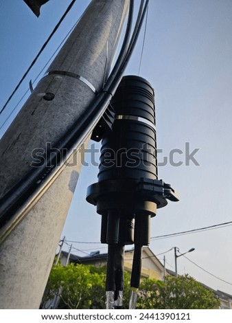 black cylindrical power booster box outdoor by the street pole.