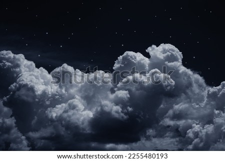Black dark blue night sky with stars. White cumulus clouds. Moonlight, starlight. Background for design. Astrology, astronomy, science fiction, fantasy, dream. Storm front. Dramatic.