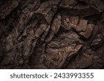 Black dark brown gray stone rock granite basalt texture background. Mountains surface. Close-up. Cracked broken crumbled.