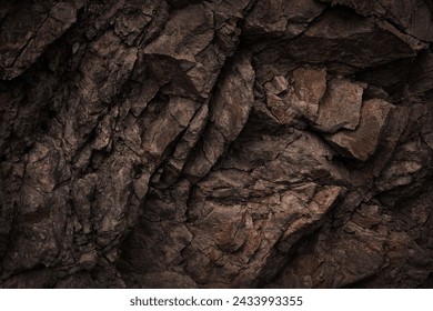 Black dark brown gray stone rock granite basalt texture background. Mountains surface. Close-up. Cracked broken crumbled.