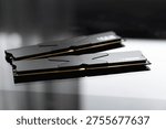 Black DDR5 RAM memory modules placed on a dark, glossy surface. RAM shortages on the market, rising prices, and increased demand driven by the growing need for AI training.