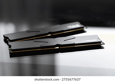 Black DDR5 RAM memory modules placed on a dark, glossy surface. RAM shortages on the market, rising prices, and increased demand driven by the growing need for AI training.