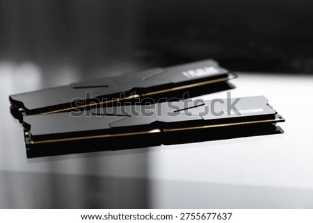 Black DDR5 RAM memory modules placed on a dark, glossy surface. RAM shortages on the market, rising prices, and increased demand driven by the growing need for AI training.