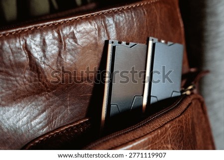 Black DDR5 RAM memory modules placed inside a brown leather bag pocket. RAM shortages on the market, rising prices, and increased demand driven by the growing need for AI training.