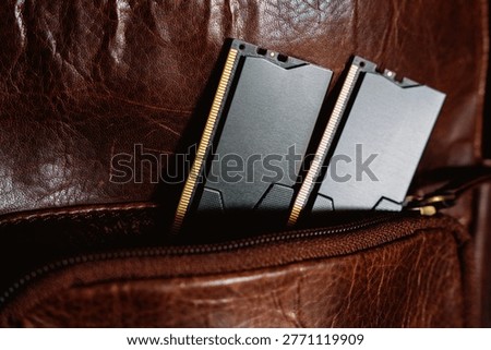 Black DDR5 RAM memory modules placed inside a brown leather bag pocket. RAM shortages on the market, rising prices, and increased demand driven by the growing need for AI training.