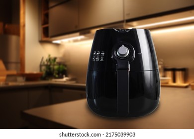 a black deep fryer or oil free fryer , air fryer appliance is on white marble table in nice interior design kitchen dinning room of the house during cooking dinner for family member in Christmas party - Shutterstock ID 2175039903