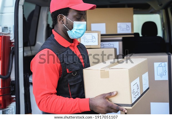 Black delivery man wearing safety mask for\
coronavirus prevention - Focus on\
face