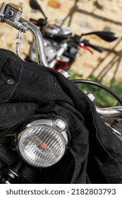 Black Denim Jacket Thrown On The Handlebars Of A Motorcycle