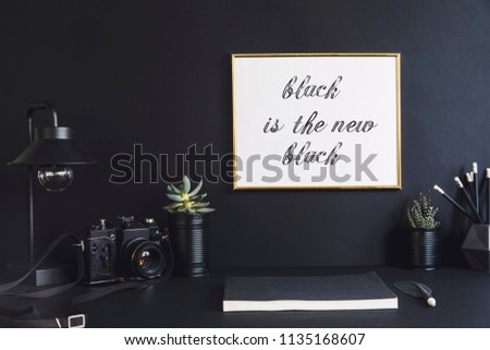 Black design room with mock up poster frame, plants in black cans, notebook and accessories. Modern and stylish black interior.