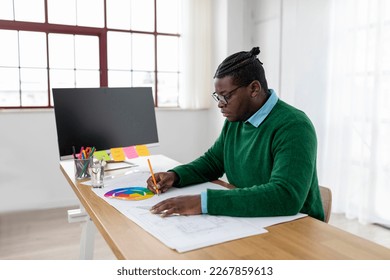 Black Designer Man Drawing Looking At Papers And Color Palette On Table Sitting In Modern Office  Side View Shot Of Male Architect Working On A Plan At Workplace 