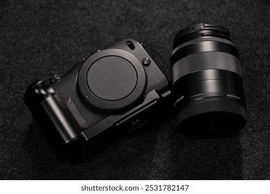 Black digital camera. Camera in hands. Camera on black background. Gray background. Modern technologies. Photographer. Camera body. Lens