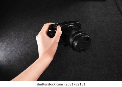 Black digital camera. Camera in hands. Camera on black background. Gray background. Modern technologies. Photographer. Camera body. Lens