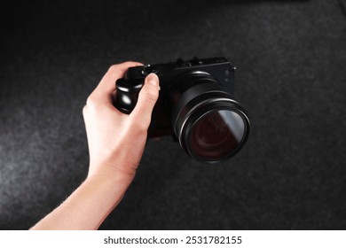 Black digital camera. Camera in hands. Camera on black background. Gray background. Modern technologies. Photographer. Camera body. Lens