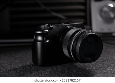 Black digital camera. Camera in hands. Camera on black background. Gray background. Modern technologies. Photographer. Camera body. Lens