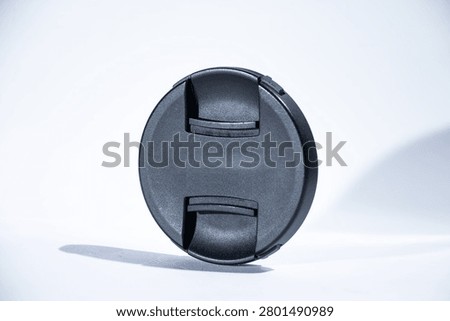Black digital camera lens cap with white background.