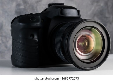 Black digital camera on a table with grunge background.