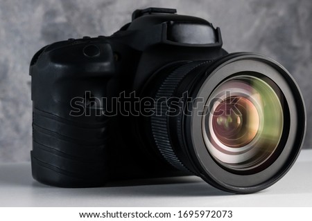 Black digital camera on a table with grunge background.