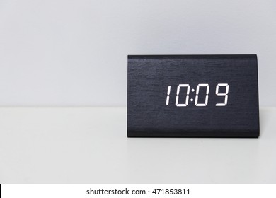 Black digital clock on a white background showing time 10:09 (ten hours nine minutes)
