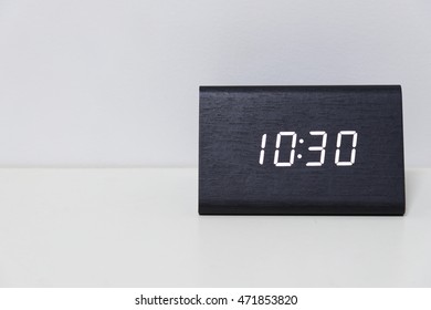 Black digital clock on a white background showing time 10:30 (ten hours thirty minutes)