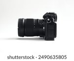 Black digital mirrorless camera with blank LCD and buttons. Side view, isolated on a white background. Full depth of field.