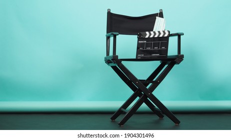 BLACK director chair with Clapperboard or movie Clapper board and face mask on green or Tiffany Blue and black floor background.it use in video production or movie and cinema industry. 