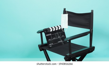 BLACK director chair with Clapperboard or movie Clapper board and face mask on green or Tiffany Blue background.it use in video production or movie and cinema industry. 