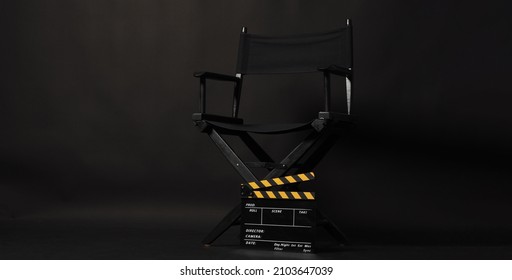 Black Director Chair With Black And Yellow Clapper Board Or Movie Slate Isolated On Black Background.No People