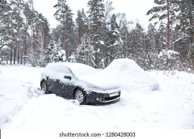 Black dirty car under the snow in forest. Heavy snowfall. Frozen car in snowdrift. winter problems to start engine