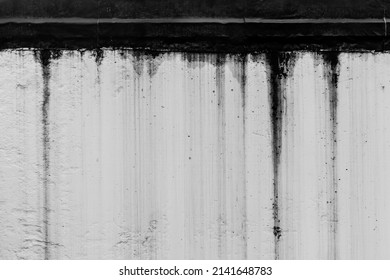 Black dirty spots of fuel oil flow liquid down spill the white old wall surface chemical industry streak background.