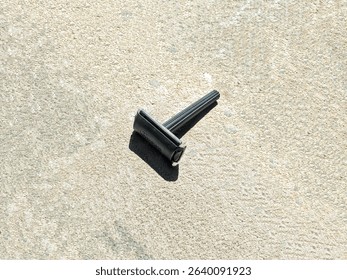 A black disposable razor lies on a textured surface, designed for shaving and personal grooming with a simple, lightweight build.
						
						