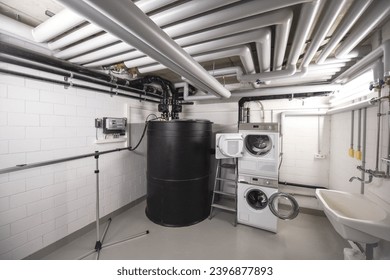 black disposal tank and washingmachine next to many sewage pipes and pump pressure line