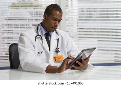 Black Doctor At Desk With Electronic Tablet, Horizontal