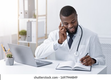 Black Doctor Talking With Patient On Mobile Phone, Working At Clinic, Taking Notes, Empty Space