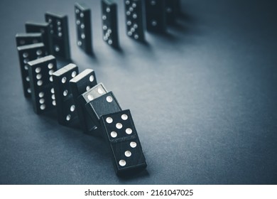 Las piezas de dominó negro se encadenan sobre un fondo de mesa oscuro. concepto de efecto dominó