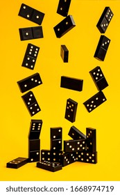 Black Dominoes Flying On Yellow Background, Closeup Scattered Dominoes On A Yellow Board Game, Game Night Dominos Table Game