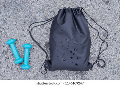 Black Drawstring Backpack, Bag For Sport And Fitness And Dumbbells On The Ground, Top View