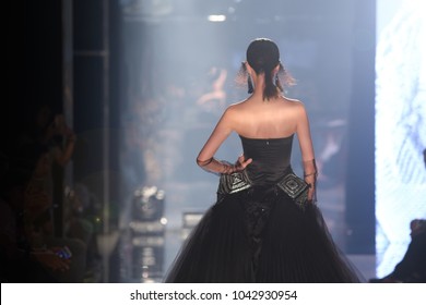 Black dress Model walk back on mirror Runway Fashion Show catwalk with reflection on floor lighting along walk way, background stage ramp, copy space for text logo